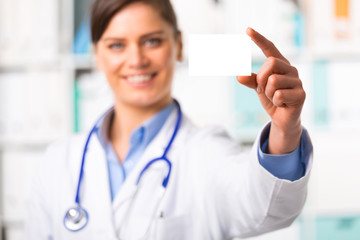 Young female doctor with blank business card