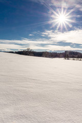 Die Wintersonne erstrahlt über den verschneiten Feldern im Voralpenland