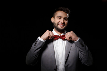 Young successful businessman correcting butterfly smiling over black background.