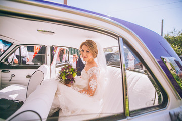  portrait of a pretty bride in retro car. Sunny day. Violet and white car color.