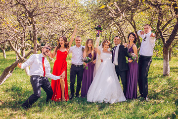 Naklejka premium beautiful newlyweds with their friends standing together