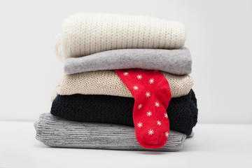 stack of sweaters with one red sock