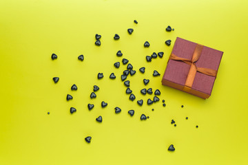 Small gift box with black hearts on a yellow background