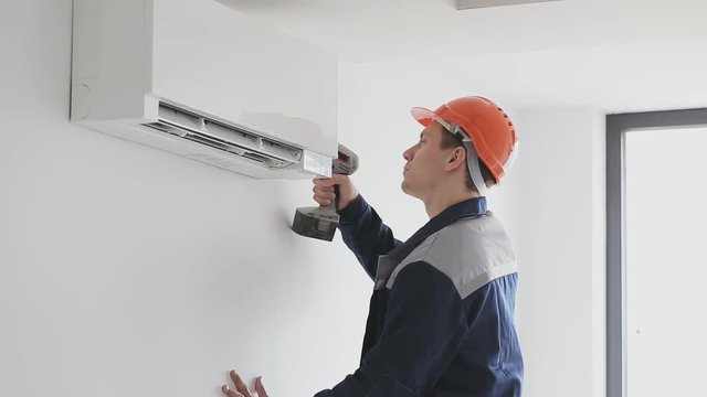 Repairman fixing air conditioning indoor