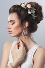Beauty portrait of an elegant bride with a wreath of flowers in a hairstyle isolated on gray background.