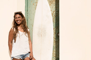 Fototapeta premium girl stand with a surfboard in front of grunge door.