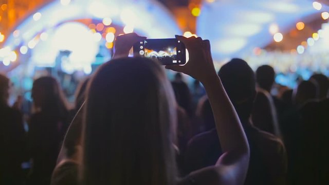 People recording video of concert on smartphones