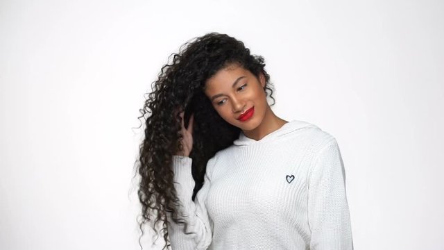 African woman in white sweater  posing in studio and playing with her hair