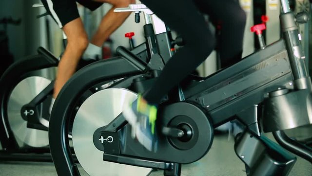 Close-up - sports people pedaling on the exercise bicycle in the gym
