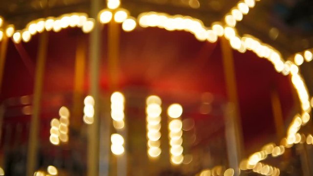Out of focus video of vintage carousel with bright light bulbs