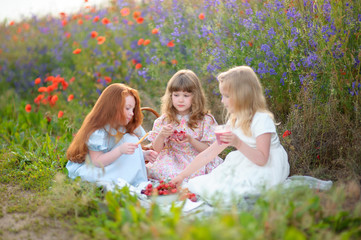 Happy kids eating strawberry cocktail outdoors in poppy field
