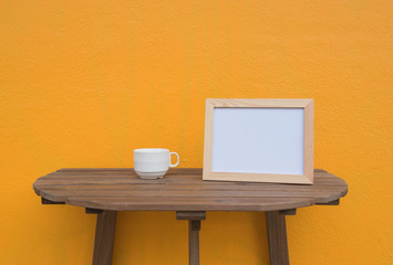 photo Frame and cup on a wooden on Yellow background .