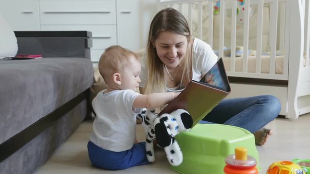 Cute smiling baby watching photographs in photo album with his mother at living room