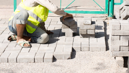 mason worker making sidewalk pavement with stone blocks