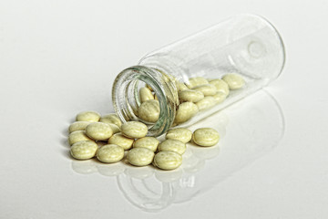 Prescription Medication Pain Pills spilled out of Glass Drug Bottle on white.