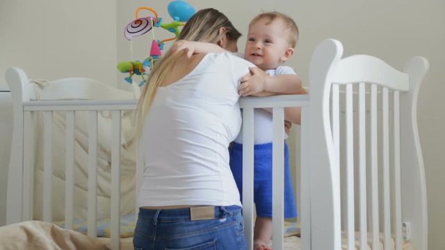 Cute toddler boy laughing being tickled by his mother in the crib