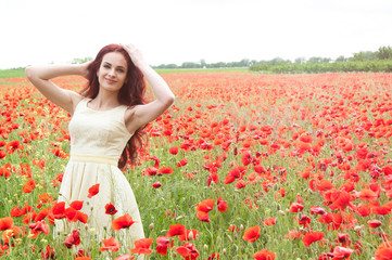 Naklejka na ściany i meble Beautiful redhead woman on a poppy field