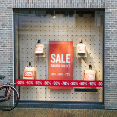 sale signs on paper bags in display window of clothing store