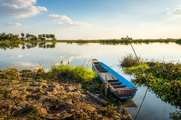 Obraz premium wooden rowboat in the calm water of lake at beautiful sunset