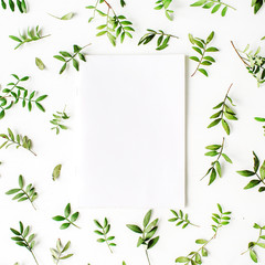 Paper blank, green branches and leaves on white background. Flat lay, top view