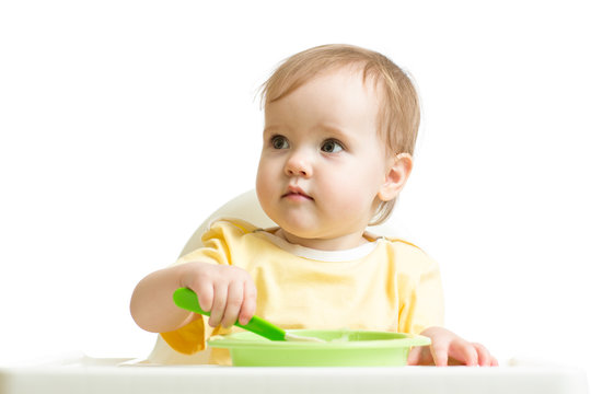 Baby girl eating yogurt or puree isolated on white background