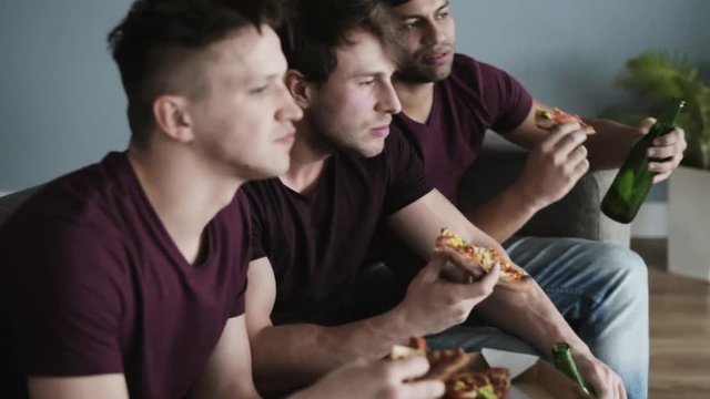 Guys having pizza and beers while sports competition 