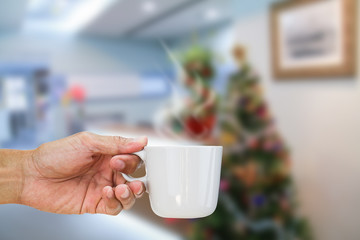 Hand holding hot coffee cup on blurred office background