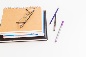 Glasses on notebooks with pen and pencil on white background