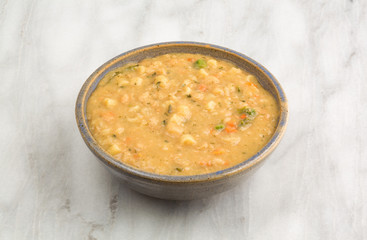 White bean soup in a bowl atop a gray marble table top.