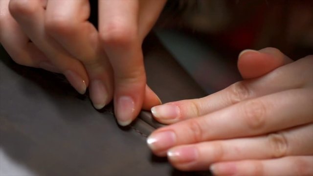 Closeup view of woman's hands creating someting from leather in the workshop