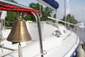 Bronze bell hanging on a yacht standing at the pier. Transport