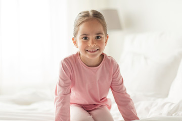 happy little girl on bed at home bedroom