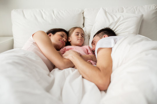 Happy Family Sleeping In Bed At Home