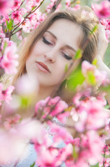 Portrait of young woman in the flowered garden in the springtime. Tender and beautiful posing.