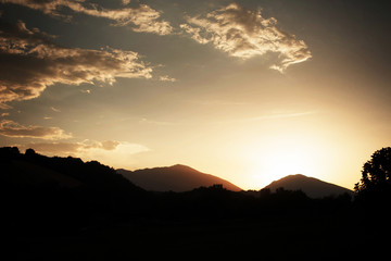 Lonelu clouds cross shiny evening sky over mountains