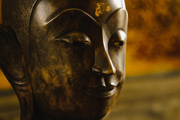 close up face on buddha head statue with Bokeh background and lighting effect.      Selective focus face buddha statue.