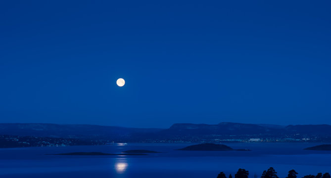 Full moon over the ferry which approaches its harbour