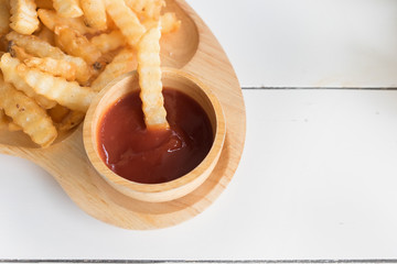 Top view french fries with ketchup in wooden dish on white wooden table