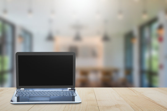 Computer laptop on wooden table top on blurred room background