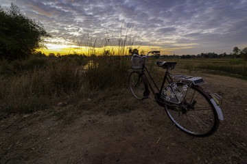 Fototapeta premium Vintage bicycle on local road with sunrise light background
