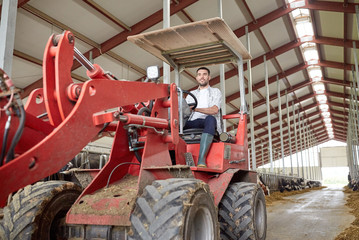 man or farmer driving tractor at farm
