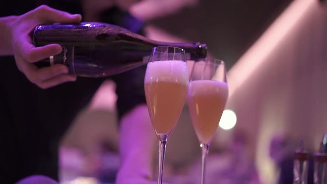 the bartender pours champagne into glasses