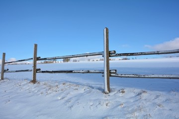 Holzzaun im Winter mit Schnee und blauem Himmel