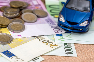 blue toy car with euro bills and coin.