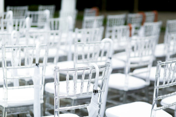 Look from behind at white plastic chairs with umbrellas hanging