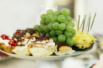 Green grape lies on plate with baked sweets