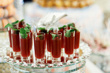 Glasses with berry drinks stand served on round glass dish