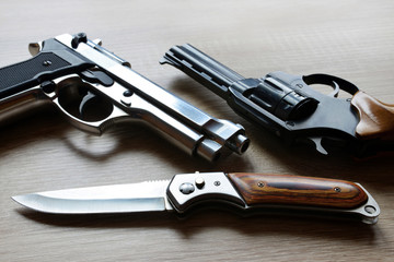 Black revolver pistols with knife on wooden board.