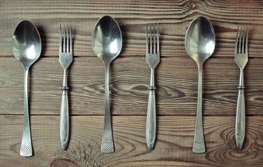 set of spoons and forks on a wooden table.
