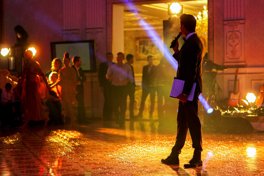 Man with microphone stands in the middle of sparkling dancefloor